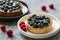 Delicious blueberry tartalets with vanilla cream on black and white plates  on a grey background. Top view.