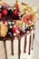 Delicious Boho Drip Cake with fruits and flowers on top on a white table