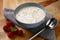 Delicious bowl of porridge and raspberrys shot on a wooden board with a napkin and spoon