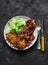 Delicious breakfast, brunch - latkes potatoes, fried bacon and green salad on a dark background, top view