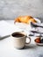 Delicious breakfast - the cup of coffee, croissant, berries and open magazine on the table at the grey background. Copy space