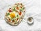 Delicious breakfast - flatbread with fried egg, greek yogurt, chili sauce and cheese on light background, top view