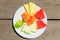 Delicious breakfast of fresh fruit on a plate - watermelon, melon, lime, papaya, pineapple and mint on old wooden background