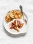 Delicious breakfast - Greek yogurt with rhubarb sauce and mini pancakes on a light background, top view