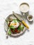 Delicious breakfast - sandwich with ham, tomato, poached egg, arugula and coffee on a light background, top view