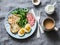 Delicious breakfast or snack - salami sausage, boiled egg, arugula, grilled bread and coffee on a gray background,