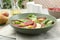 Delicious bresaola salad in bowl, fork and ingredients on light table, closeup