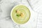 Delicious broccoli cream soup with croutons served on marble table, top view