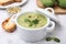 Delicious broccoli cream soup with pumpkin seeds on white marble table