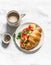 Delicious brunch - coffee with cream and croissant sandwich with cream cheese, salmon and boiled egg on a light background, top