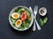 Delicious brunch - spinach, smoked salmon, soft boiled egg on a dark background, top view.