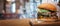 Delicious burger on the background of the interior of the burger shop. Fresh hamburger with salad, meat, cheese and sauce on the