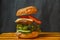 Delicious burger with flying ingredients on dark concreate background