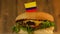 Delicious burger with small Colombian flag on top of them with toothpicks. Yummy hamburger rotating.