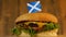 Delicious burger with small Scottish flag on top of them with toothpicks. Yummy hamburger rotating.