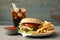 Delicious burger, soda drink and french fries served on grey table