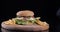 Delicious burger suddenly appears in dark frame on wooden board. Male hands in latex gloves chef put push on black table