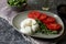 Delicious burrata cheese with tomatoes and arugula on grey table, closeup