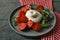 Delicious burrata cheese with tomatoes and arugula on grey wooden table, closeup
