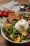 Delicious burrata salad with colorful cherry tomatoes, croutons and arugula on wooden table, closeup