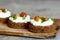 Delicious canape with soft cheese and mushrooms on a board on a wooden background