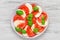 Delicious caprese salad with ripe tomatoes and mozzarella cheese with fresh basil leaves. Italian food
