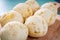 Delicious cheese bread, typical Brazilian dish, on wooden board and table with green background