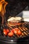 Delicious cheeseburger with tomatoes cooking on hot flaming grill. Barbecue. Restaurant