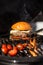 Delicious cheeseburger with tomatoes cooking on hot flaming grill. Barbecue. Restaurant