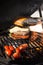 Delicious cheeseburger with tomatoes cooking on hot flaming grill. Barbecue. Restaurant