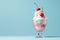 Delicious cherry-topped ice cream sundae in a glass bowl against a pastel blue background with copy space