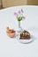 Delicious chocolate cake and dessert near with flowers on white table in cafe