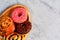 Delicious chocolate donuts and buns with poppy seeds and raisins lie on an oval wooden tray and a gray concrete surface