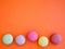 Delicious colorful Macarons almond cookies diffrent colors on orange background