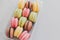 delicious colorful macaroons in plastic box on trendy pastel gray paper. tasty pink, yellow, green and brown macaroons. space for