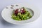 Delicious combination of arugula, beets, cheese and vinaigrette on a white ceramic plate