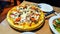 delicious combination pizza with salami, olives, tomatoes, minced meat, mushrooms and cheese on the table