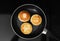 Delicious cottage cheese pancakes in frying pan on cooktop, top view