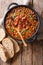 Delicious cowboy stew of beans with ground beef, bacon in a spicy sauce closeup in a bowl. Vertical top view