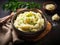 Delicious creamy mashed potatoes with butter, fresh herbs in a ceramic bowl on a wooden cutting board on dark background. Top view