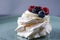 Delicious crispy meringue cake with fresh berries. Raspberries and blueberries in the famous dessert of Anna Pavlova.