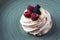 Delicious crispy meringue cake with fresh berries. Raspberries and blueberries in the famous dessert of Anna Pavlova.