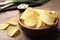 Delicious crispy potato chips in bowl on table, closeup