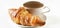 Delicious croissant on a ceramic saucer with coffee in a cup