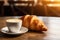 Delicious croissant and cup of coffee on wooden table