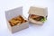 Delicious crunchy french fries and a large juicy burger. in open boxes made from sustainable cardboard. on white