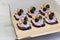 Delicious cupcakes with lilac  cream with blackberries and rosemary  in a box for cakes