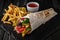 A delicious doner donair kebab wrap with meat, lettuce, tomato, red onion and sauce with french fries