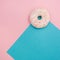 Delicious donut with icing and candy on a pink and blue background.