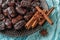 Delicious dried Iranian dates, few cinnamon sticks and star anise on a black ceramic plate over turquoise cloth. Sweet vegetarian